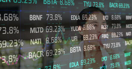 Woman in blazer analyzing tickers, monitoring figures in office through glass partition, copy space....
