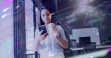 Standing business casual woman holding smartphone in open-plan office, near glass partition overlay. Technology, collaboration, productivity, modern, workspace, innovation, communicationの写真素材