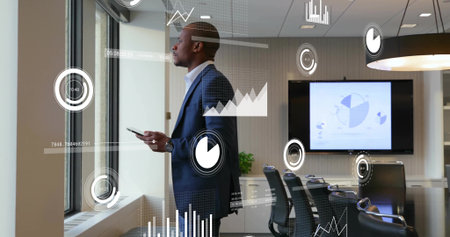Gazing professional in suit holding smartphone in conference room by monitor, with data overlays. Corporate, technology, modern, analytics, business, presentation, workspaceの写真素材