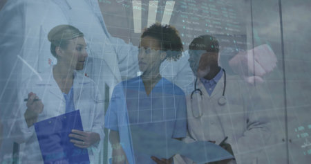 Reviewing digital charts, team in lab coats, scrubs in hospital corridor with clipboard, tablet. Medical, teamwork, collaboration, clinical, diagnostics, professionalism, healthcareの写真素材