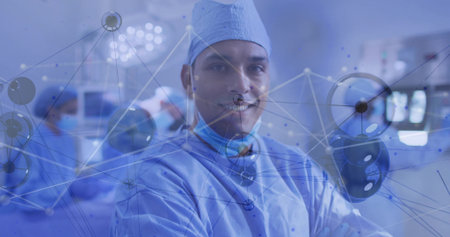 Standing and facing camera Hispanic surgeon in operating room with lights and network overlay. Medical, innovation, clinical, technology, teamwork, precision, healthcareの写真素材