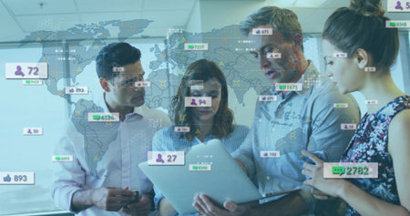 Four colleagues analyzing metrics on laptop in meeting room, with world map, floating social icons. Collaboration, teamwork, analytics, data visualization, digital communication, business meeting, modern officeの写真素材