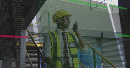 Standing worker wearing safety vest and helmet on scaffolding stairs inside building, holding pen....