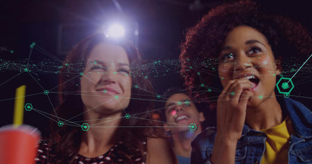 Watching trio in dark movie theatre, with red cup, popcorn, digital overlay and projector lamp. Cinema, entertainment, technology, social, futuristic, ambiance, relaxationの写真素材