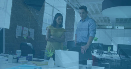 Viewing laptop screen, office colleagues collaborating at open plan office, with notebooks, plants. Professional, teamwork, collaboration, workspace, modern, productivity, corporateの写真素材