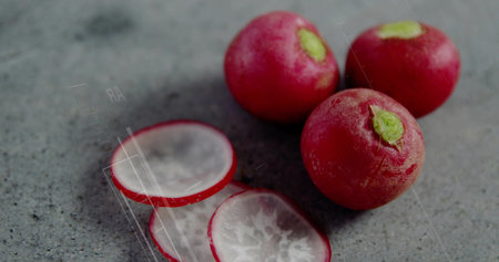 Arranging whole red radishes and sliced rounds on smooth gray stone countertop, food preparation. Vegetables, culinary, minimalist, fresh, healthy, kitchen, organicの写真素材