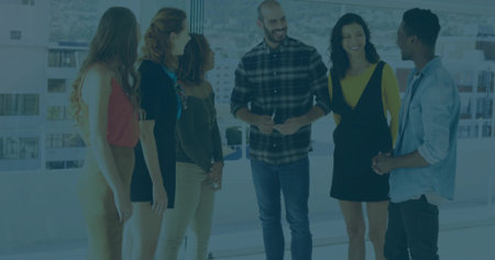 Standing staff wearing work attire engaging in discussion at modern office windows, city view. Collaboration, teamwork, corporate, urban, professional, modern, productivityの写真素材