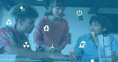 Three teammates sitting at office table, reviewing turbine model and energy icons. Collaboration, innovation, environmental, technology, teamwork, professional, sustainabilityの写真素材