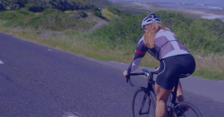 Riding woman cyclist pedaling on country road, with helmet, jersey, shorts, road bike, copy space. Adventure, outdoor, fitness, leisure, motion, scenic, healthの写真素材