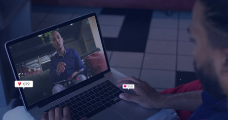 Bearded man watching host on laptop screen in lounge area, with heart icon and location pin....