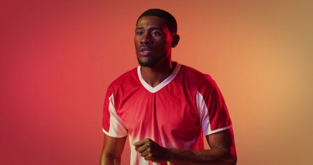 Posing African American athlete breathing deeply on gradient backdrop, showing red and white jersey. Dynamic, determined, energetic, vibrant, motivational, fitness, studioの写真素材