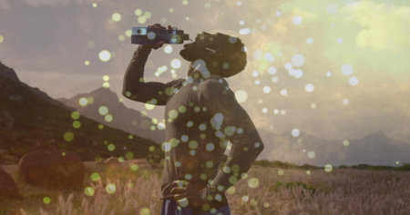 Hydrating athlete in sportswear in rural meadow at sunset, with reusable water bottle and hay bales. Outdoor, vitality, serenity, landscape, fitness, wellness, natureの写真素材