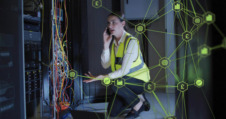 Kneeling tech wearing safety vest checking cables in data center, neon green overlay and smartphone....
