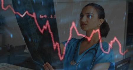 Holding X-ray film with red graph overlay, Indian doctor in blue scrubs at hospital, copy space....