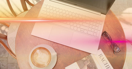 Silver laptop basking in dappled sunlight on cafe terrace, with coffee cup, book and eyeglasses. Modern, cozy, tranquil, minimalist, lifestyle, workspace, outdoorの写真素材