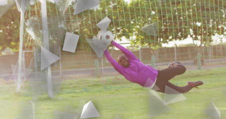 Diving goalkeeper wearing purple jersey red cleats on grass pitch, catching soccer ball in goal net. Athleticism, action, dynamic, sport, competition, vitality, movementの写真素材