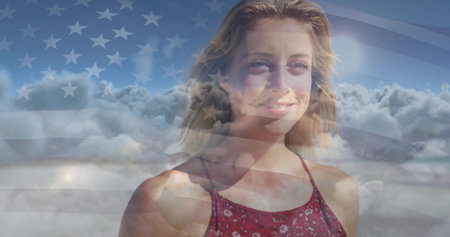 Smiling adult woman wearing red patterned sleeveless top against cloudy sky, with US flag overlay. Patriotic, resilience, hope, empowerment, patriotism, digital art, inspirationalの写真素材