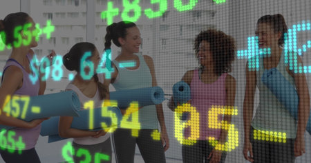 Chatting women holding yoga mats and interacting in fitness studio, with stock ticker overlay. Fitness, wellness, camaraderie, leisure, modern, vibrant, legislativeの写真素材