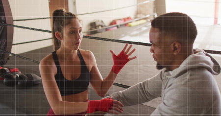 Boxer in sportswear speaking and gesturing inside gym boxing ring, with red hand wraps and gloves. Athlete, trainer, coaching, fitness, strength, competition, determinationの写真素材