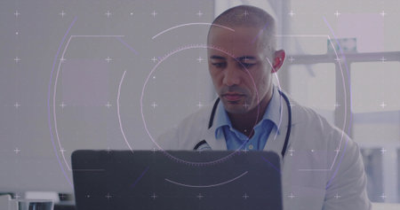 Reviewing medical data lab coat doctor using laptop in clinic office, with stethoscope, tumbler. Professional, healthcare, technology, diagnostics, clinical, consultation, modernの写真素材