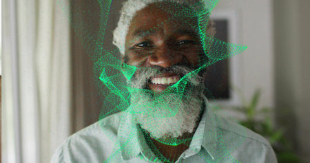 Senior man standing wearing light gray shirt in living room, with green digital mesh pattern....