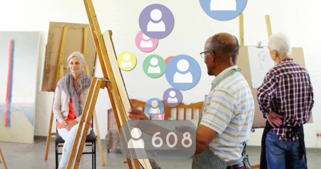 Senior artist in polo apron painting portrait on canvas in art studio, with floating numeric icons. Creative, mentorship, collaboration, realism, expressionism, interior, colorfulの写真素材