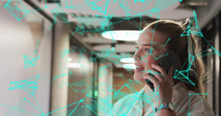 Speaking blonde woman holding phone and showing network overlay in office corridor, copy space....