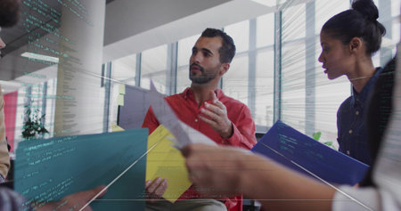 Gesturing red-shirted man discussing project at open office, with colored folders and code overlay....
