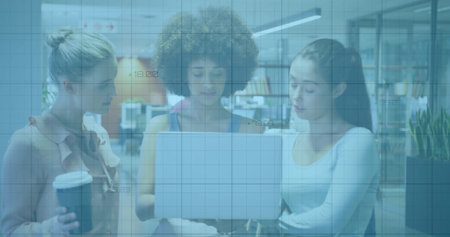 Collaborating women analyzing data on laptop in office, with grid overlay and takeaway coffee cup. Business women, teamwork, modern workspace, financial analysis, professional collaboration, digital technology, creative environmentの写真素材