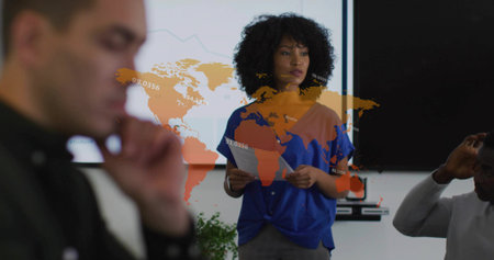 Presenting woman holding printed documents and displaying data at conference room, with world map. Business meeting, collaboration, professional, modern, strategy, analytics, teamworkの写真素材