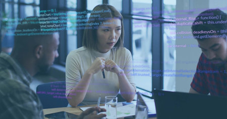 Speaking Asian woman gesturing with pen in modern office meeting room, with laptop and code overlay. Collaboration, teamwork, innovation, professional, digital, business, modernの写真素材