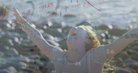 Basking adult woman wearing sweater stretching arms on rocky shoreline by water. Freedom, vitality, outdoor, inspirational, scenic, wellness, serenityの写真素材