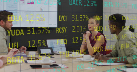 Woman wearing sleeveless burgundy top presenting market data in boardroom, with laptop and charts....