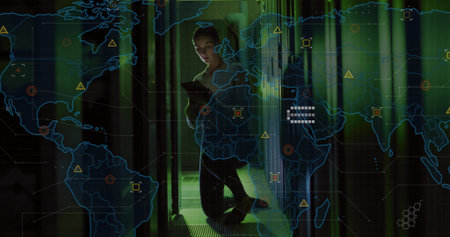 Kneeling technician monitoring racks in data center holding tablet displaying world map overlay....