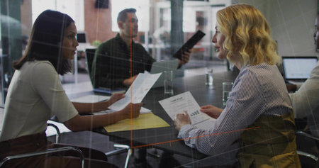 Office team sitting around glass conference table, with printed reports folder laptop water glasses....