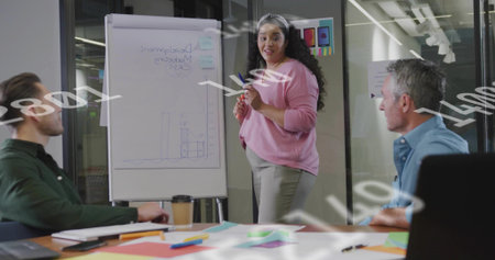 Presenting presenter wearing pink top and light trousers by flip chart in meeting room, with marker....