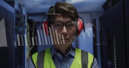 Operating servers and monitoring data charts, data center technician in yellow vest and headphones. Technology, cybersecurity, modern, digital, industry, innovation, professionalの写真素材