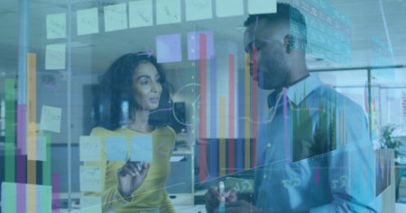 Woman and man pointing and listening at glass board with sticky notes in office, markers, charts. Collaboration, teamwork, innovation, data visualization, modern office, productivity, brainstormingの写真素材