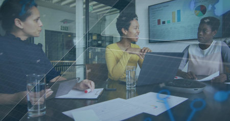 Speaking woman in yellow sweater leading meeting in modern glass conference room with laptop charts....