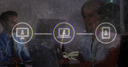 Working staff wearing suits using desktop and laptop at office desk, with network icons overlay....