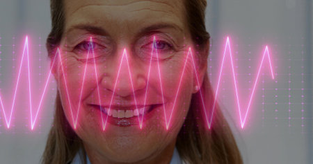 Posing senior woman wearing blue shirt smiling in studio portrait, with neon-pink ECG waveform. Portrait, medical, health, technology, vibrant, wellness, professionalの写真素材