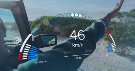 Driving Indian woman wearing dark jacket extending arm outside convertible on coastal road with HUD....