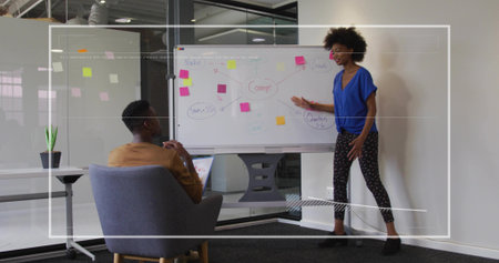Presenting Black woman gesturing toward sticky-note whiteboard in modern office area, copy space....