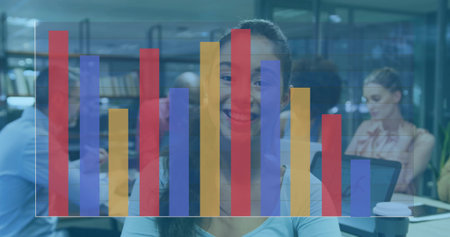 Smiling Asian woman sitting at desk in modern library, with laptop, coffee cup, bar chart overlay....