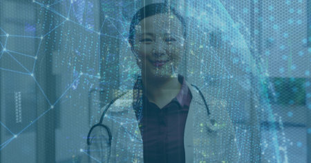 Standing Chinese doctor donning white coat in hospital corridor, stethoscope and digital overlay. Medical, technology, healthcare, futuristic, research, innovation, professionalの写真素材