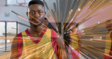 Standing basketball player holding ball center court at gym, with yellow jerseys, overhead lights. Athletes, teamwork, sportsmanship, action, training, fitness, competitionの写真素材