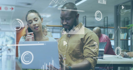 Typing African American wearing olive shirt working with colleague at open-plan office, with laptop. Collaboration, teamwork, modern, bright, professional, workspace, productivityの写真素材