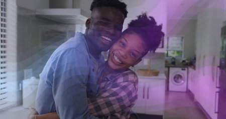 Hugging smiling couple sharing embrace in modern kitchen, with cabinets, washing machine and basket. Romantic, intimacy, warmth, cozy, domestic, lifestyle, scandinavianの写真素材