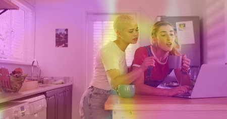 Leaning short-haired woman and her friend examining laptop screen at home kitchen island, with mugs. Casual, home environment, cozy, friendship, collaboration, modern, lifestyleの写真素材