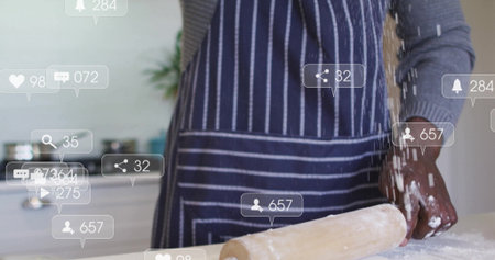 African American man in striped apron rolling dough on kitchen counter, with rolling pin. Culinary, cooking, artisan, rustic, domestic, healthy, creativityの写真素材